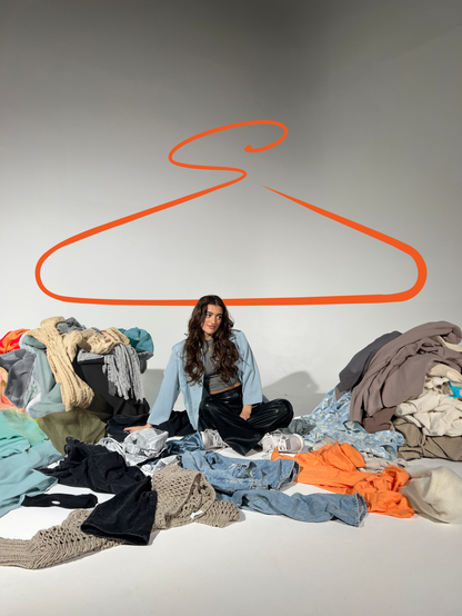 Swap Social photoshoot with model seated among donated clothing, representing circular fashion concept