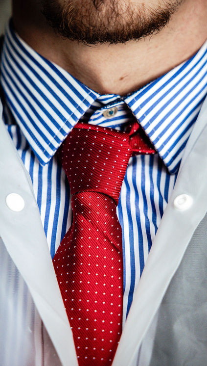 Detail shot of striped shirt and red tie worn by male model, minimalist menswear editorial