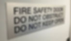 Compliance door sign displaying fire safety instructions and building regulations.