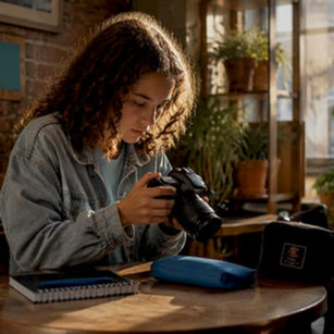 Teen girl editing photos on camera at desk