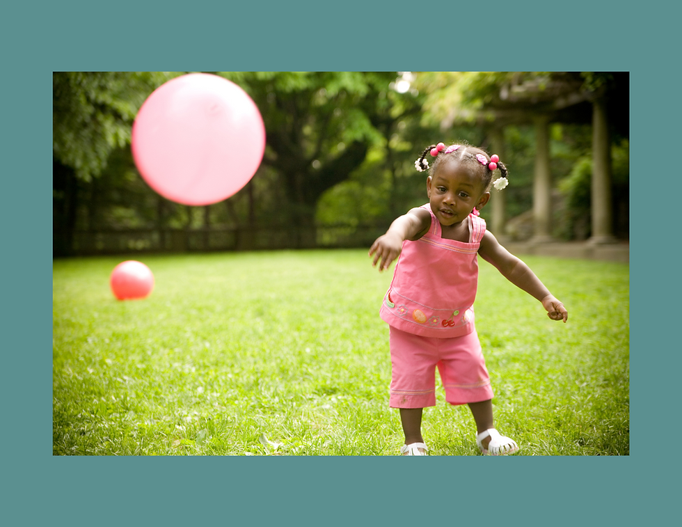 Toddler throwing a ball outside.