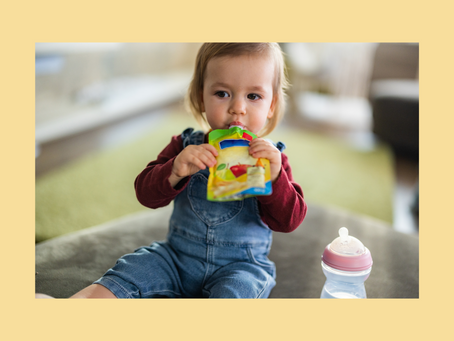Toddler sucking from a fruit pouch.
