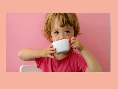 A toddler drinking from an open cup, not a sippy cup.