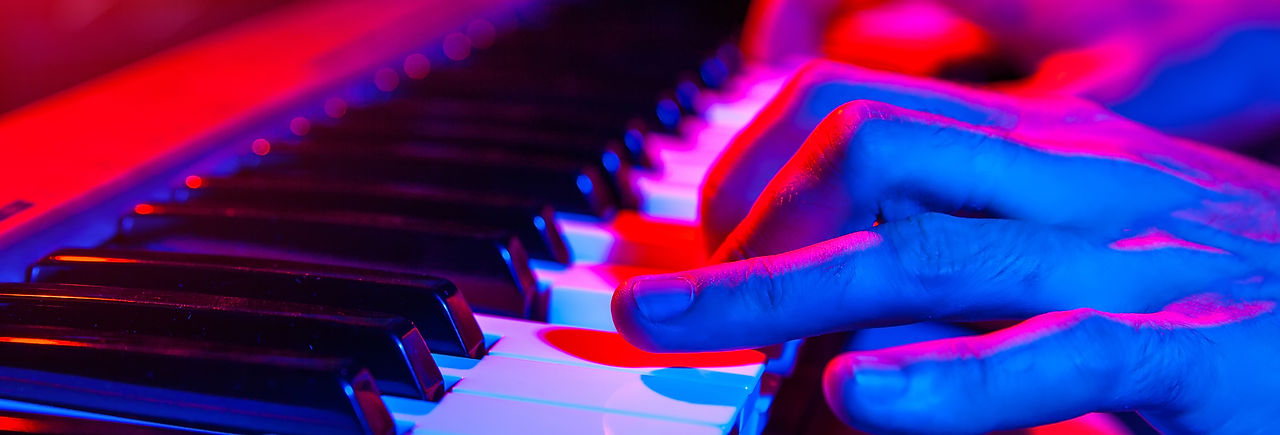 Person playing piano under concert lights.
