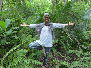 Aida in a forest surrounded by trees doing a yoga pose