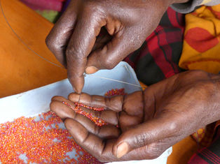 Maasai artisan stringing together a beaded product