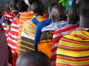 Maasai women wearing colourful, traditional fabrics standing in a line at church in Lekrumuni, rural Tanzania