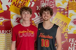 Texas Mayhem player with a Hesston College basketball player in front of the Hesston Larks recruiting backdrop.