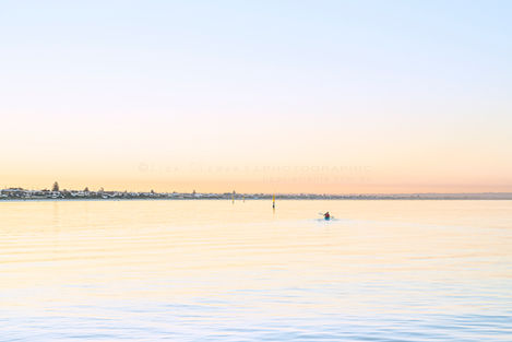 Kayaker paddling in water at sunrise, Aspendale Beach