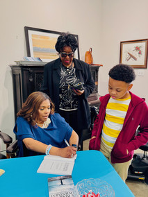 Reshone Moore signing book for guest at Re-Imagining Contentment's Book Launch Event