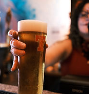 Bar host holding out pint glass towards the camera