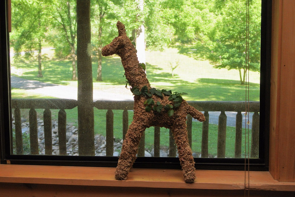 Thumbnail: Small Giraffe topiary planted; window setting view.