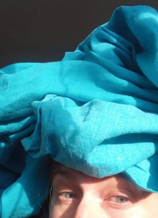 blue fabric wrapped around women head and face looking up to the sky