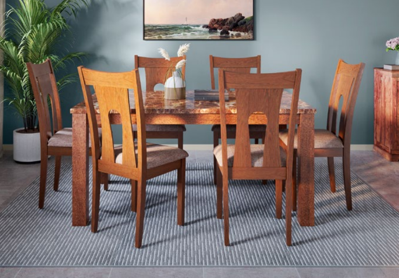 Amber dining table with four honey chairs on a blue rug.
