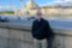 Person standing on a bridge with a Ferris wheel behind him