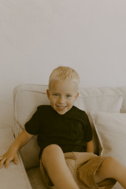 Three year old sitting on couch smiling.
