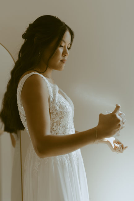 Bride spraying perfume on wedding morning.