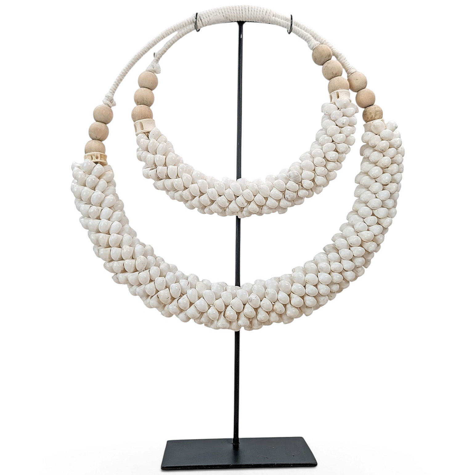 Macrame cowrie shell necklace displayed on a black metal stand