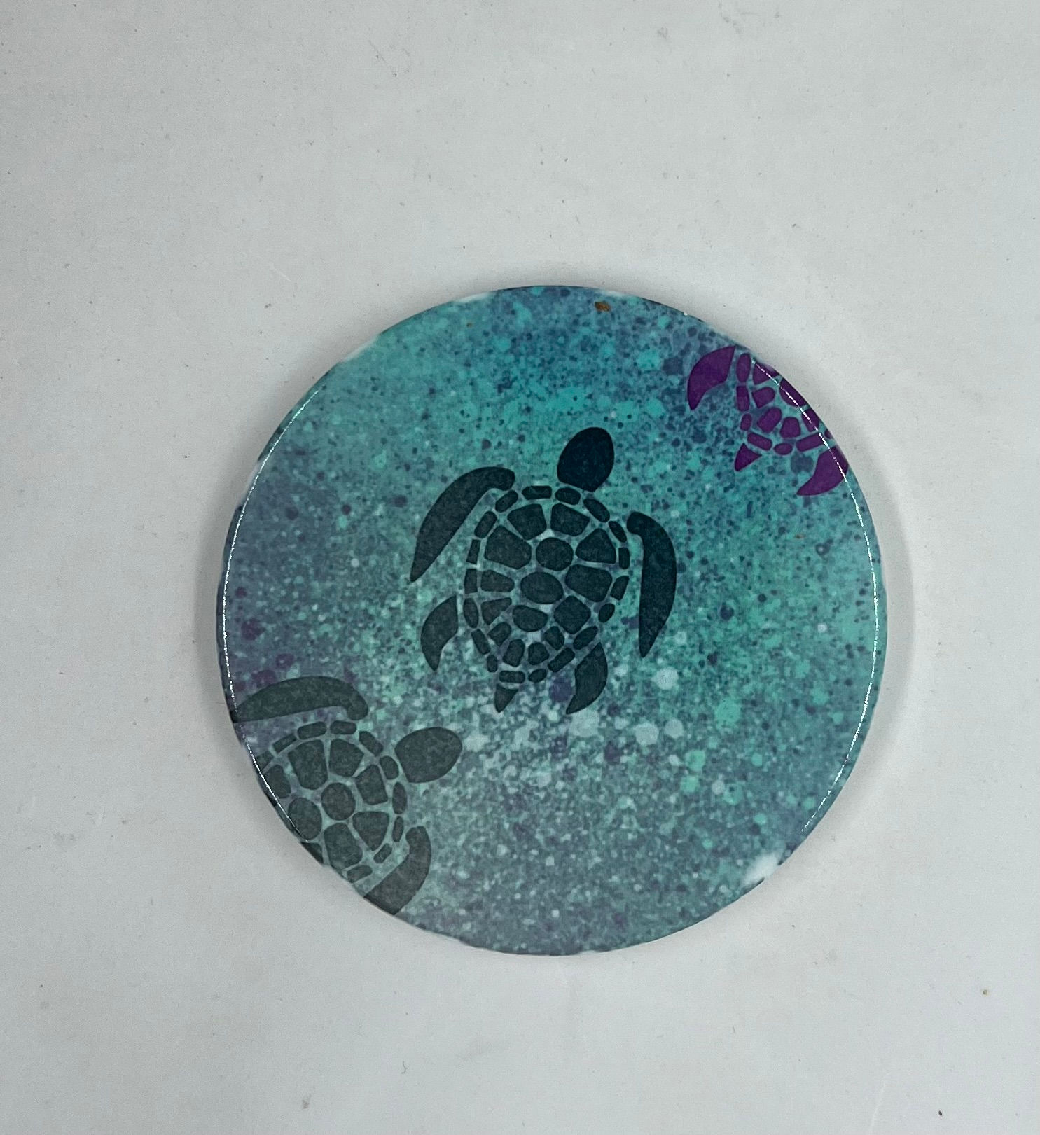 Ceramic placemat coaster with a blue and teal representation of a blue turtle swimming in the sea