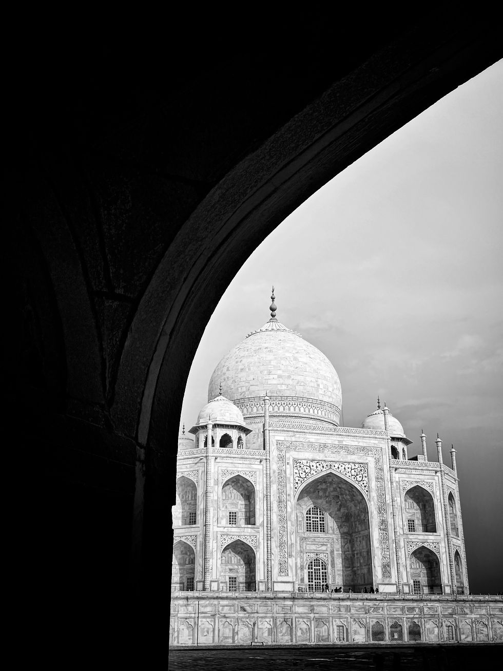 Thumbnail: Vertical black and white photo of the Taj Mahal partially framed by a dark, sweeping foreground arch.