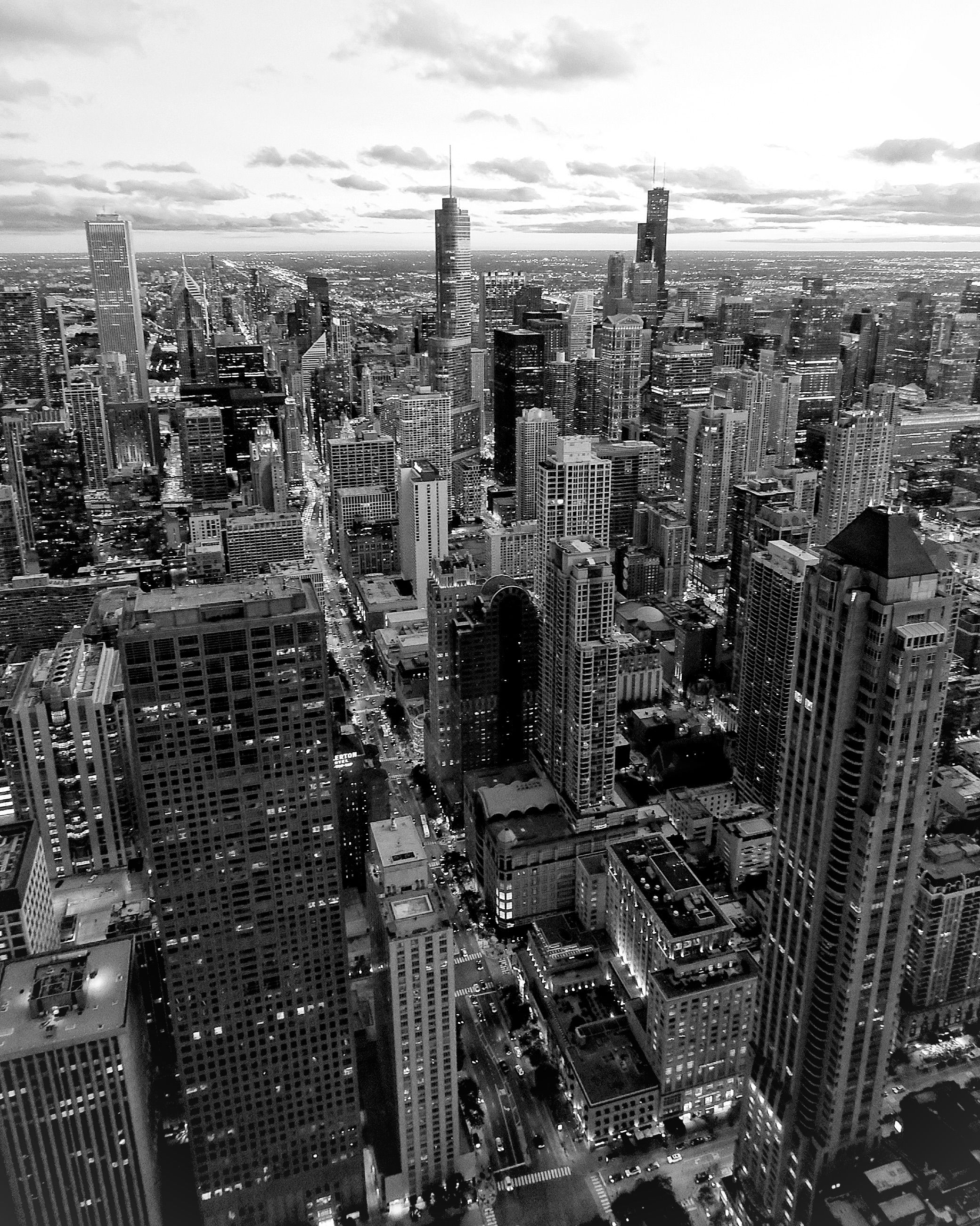 High-angle black and white aerial view of the Chicago skyline and urban grid.