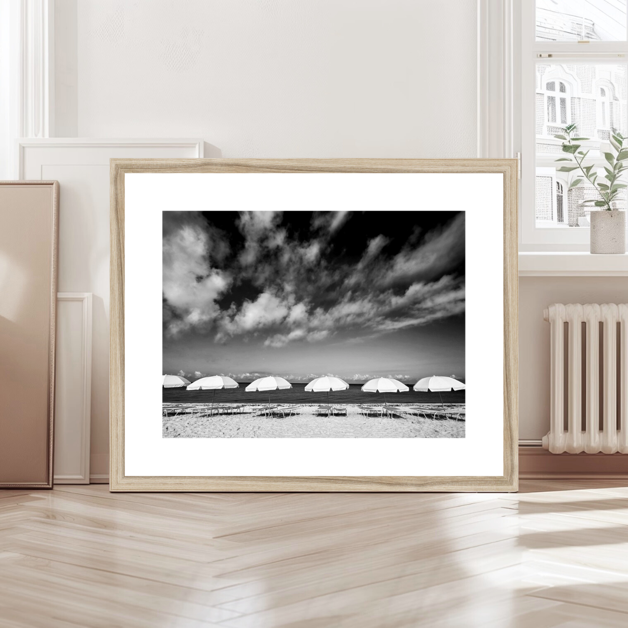 Black and white minimalist photo print of parasols lined up on beach with clouds