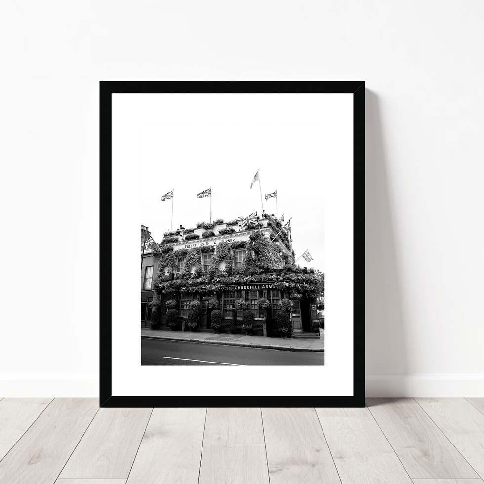Thumbnail: Black and white exterior view of The Churchill Arms pub in London covered in flowers and flags.