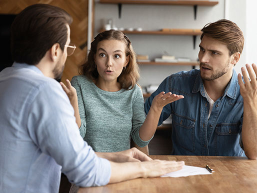 A man and woman looking concerned while talking to their real estate agent.