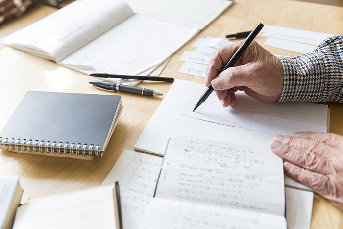 elderly man hand writing notes for his survivor's letter