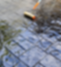 Roller with long handle being used to reseal a concrete patio
