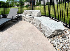 Concrete patio showing a sponge-finished texture with a lawn chair and boulders