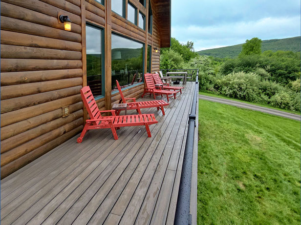 Log home deck with red outdoor lounge chairs.
