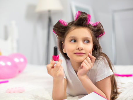 Menina com rolos no cabelo, segurando esmalte.
