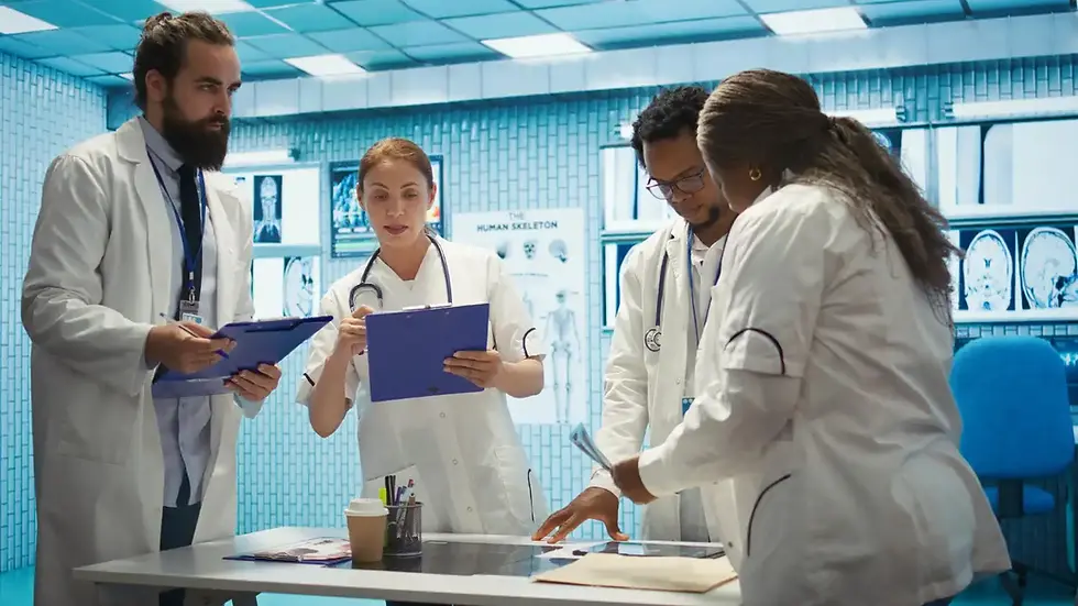 Equipe de médicos discutindo diagnóstico e plano de tratamento em uma sala de hospital moderna e bem equipada, com monitores de exames médicos ao fundo.