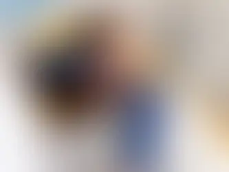 Criança no consultório odontológico recebendo atendimento odontológico de um profissional com luvas azuis, realizando exames na boca do garoto.