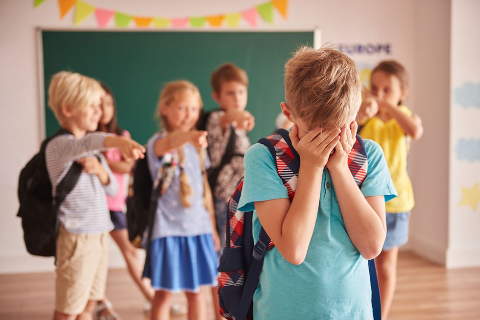 Crianças em sala de aula apontando na direção de um colega que está chorando e escondendo o rosto, mostrando um momento de bullying na escola.