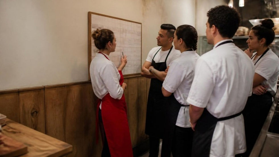 Dueña de un restaurante revisa con su equipo el tablero de turnos semanales antes de abrir.