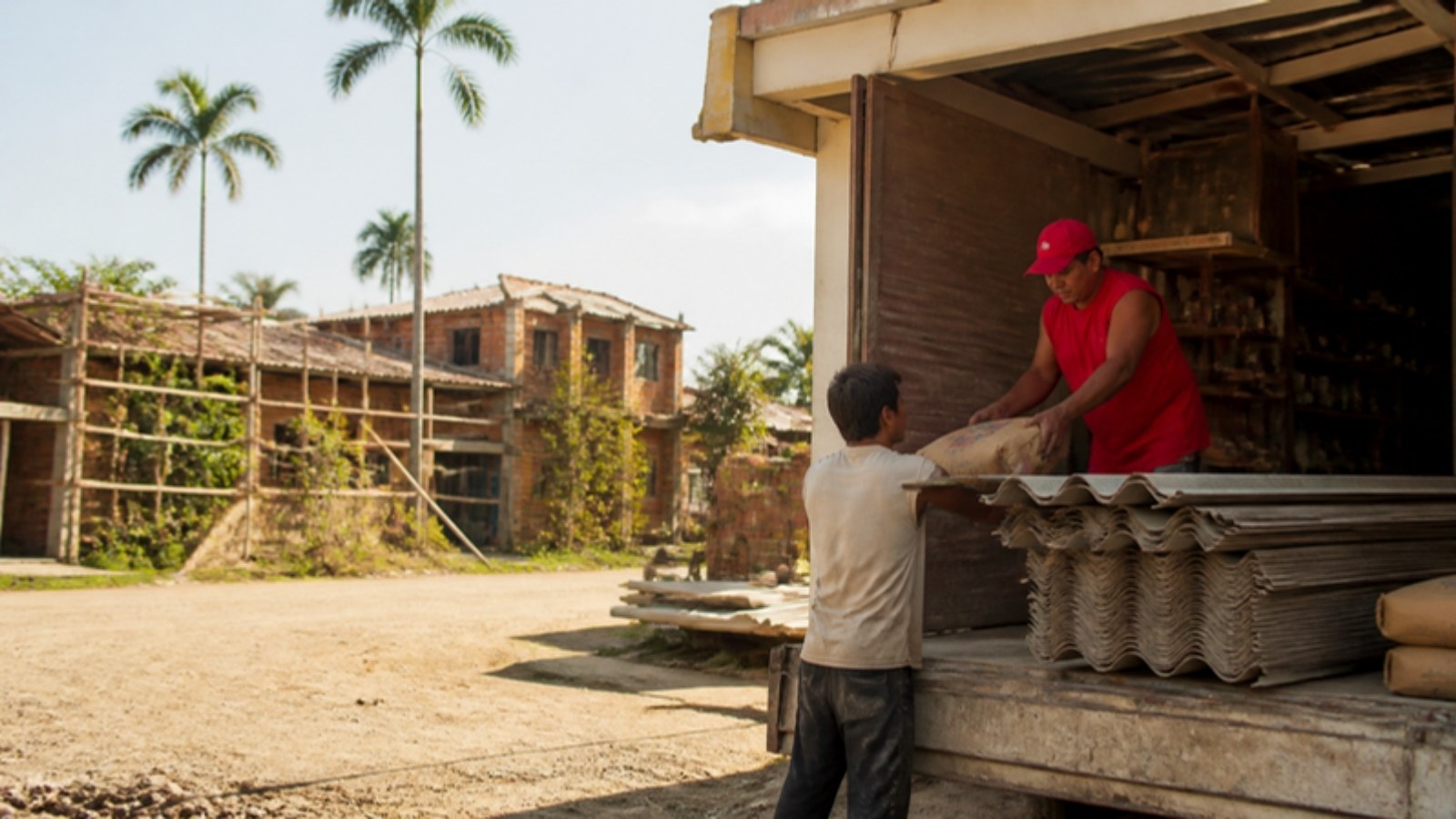 Ferretería de un municipio del Valle del Cauca despacha materiales a un maestro de obra frente a casas en reparación.
