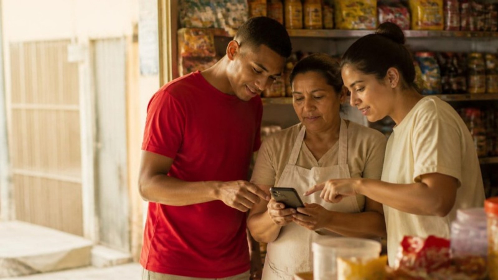 Dos jóvenes emprendedores enseñan a una tendera de Barranquilla a registrar ventas y recibir pagos en su celular