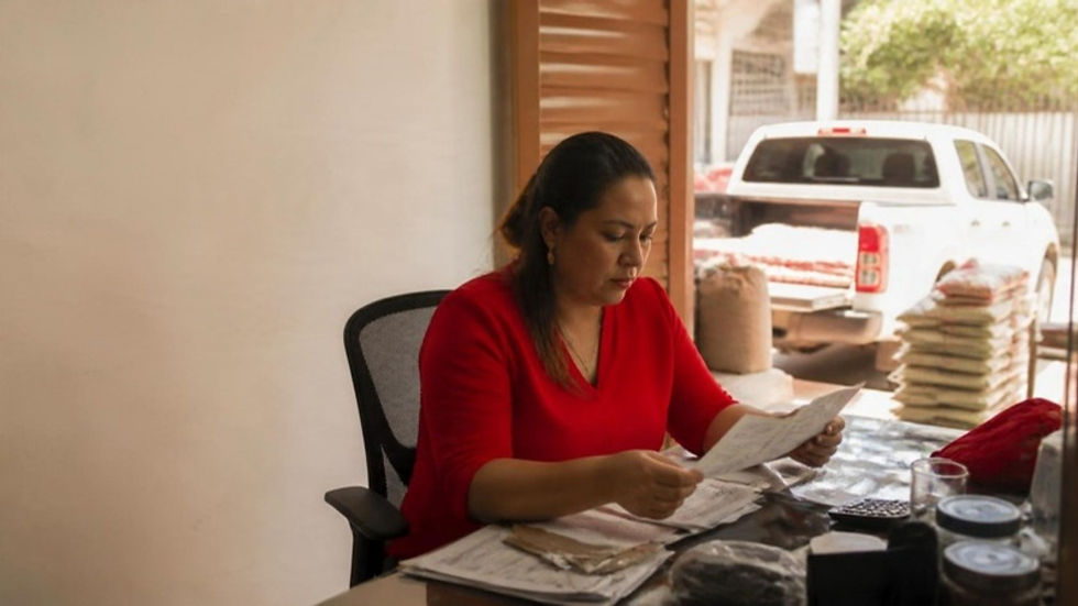 Comerciante de Barranquilla revisa sus deudas de impuestos departamentales junto a su vehículo de reparto.