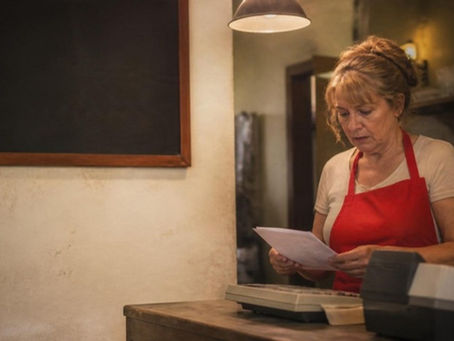Dueña de un restaurante de barrio en Rosario revisa facturas de servicios junto a la caja