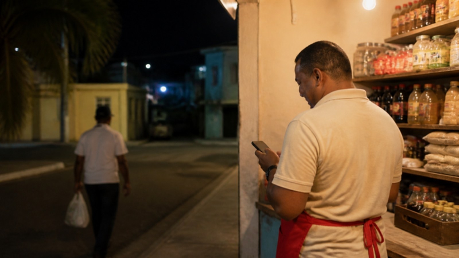 Dueño de un colmado de Santo Domingo confirma en su celular un pago de un cliente en la noche.