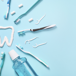 Flat lay of oral hygiene products on a light blue background, including toothbrushes, floss picks, toothpaste, and mouthwash arranged around a toothpaste outline in the shape of a tooth. Represents preventive dental care steps that can help manage side effects of GLP-1 medications like Ozempic.