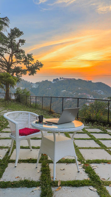 Outdoor table and chair in the lawn with trees in the background and sunset with a view of the hills.