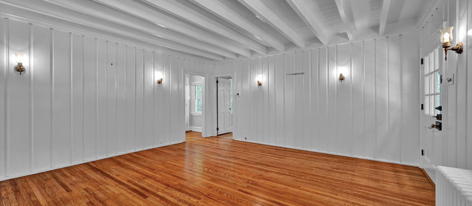 An empty room with white walls and ceiling and wood floors.