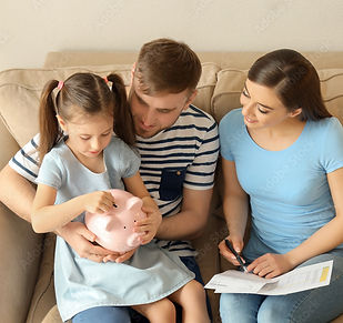 Little girl with her parents sitting on sofa and putting coin into piggy bank