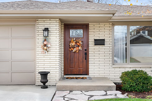 A ranch, home front door detail with a wooden front door and off white brick siding