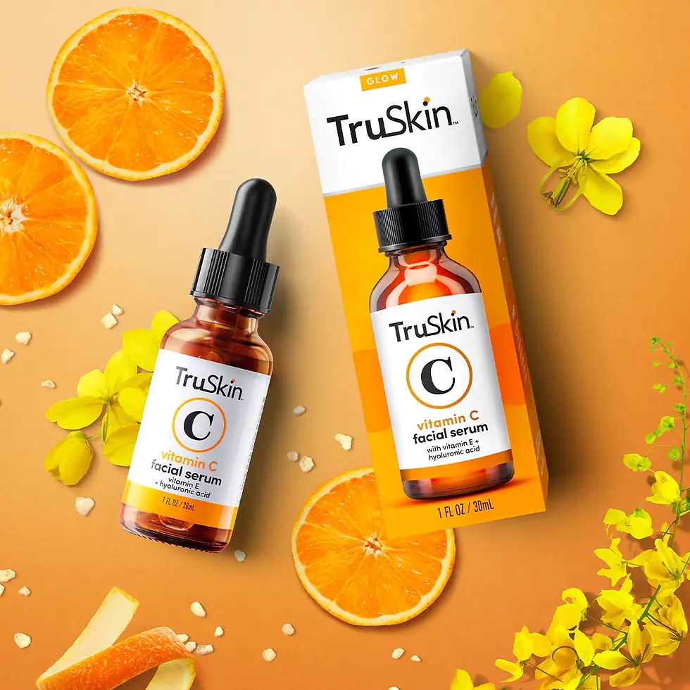 Brown bottle with black top and white and orange box of serum on an orange background with yellow flowers and orange slices.