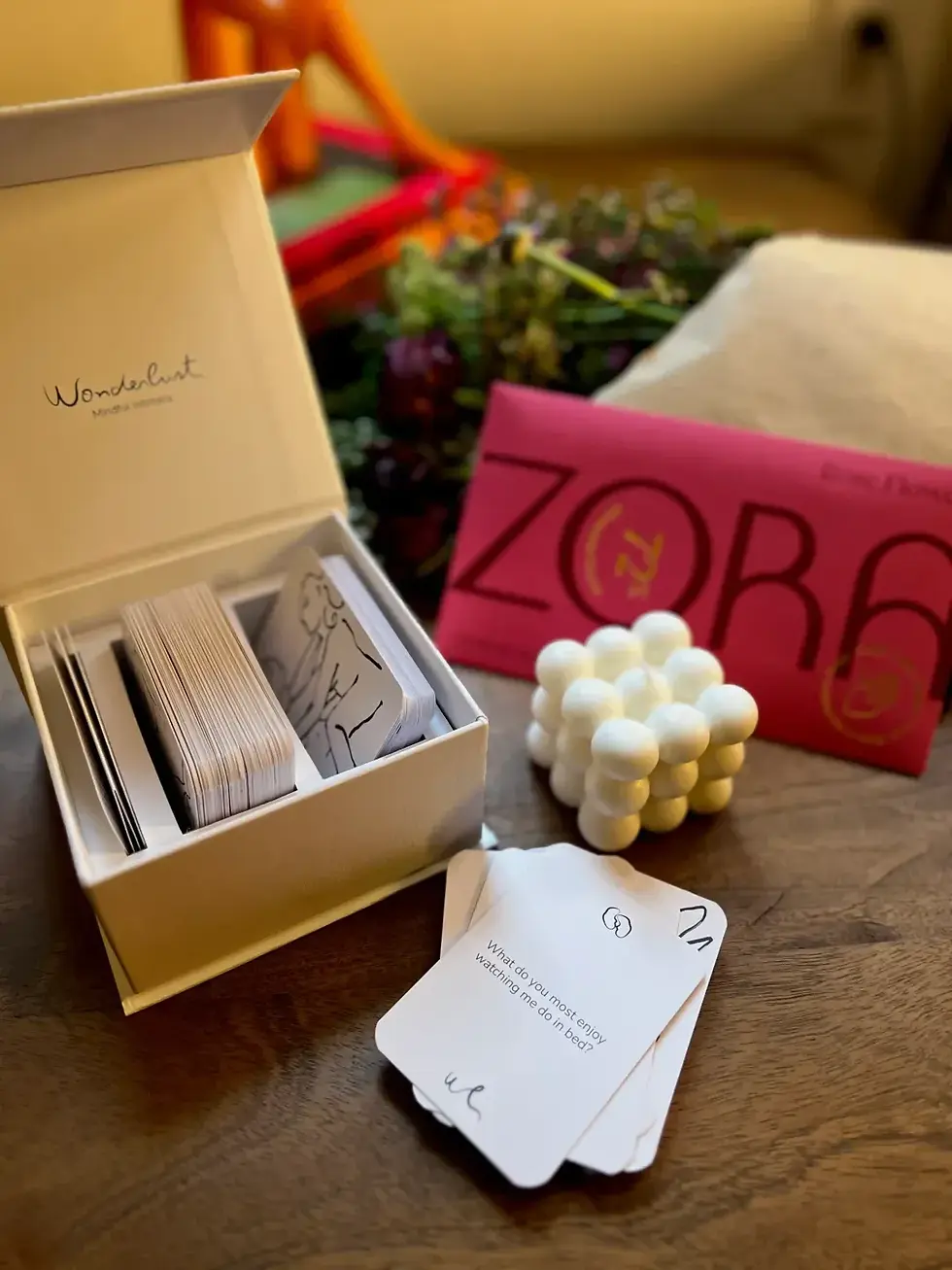Set with a cream box of white intimacy cards, a pink-wrapped bar of chocolate and an off-white candle.