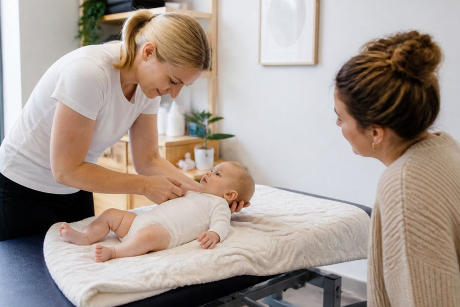 Osteopath gently examining a baby’s neck during a session to determine how many osteopathy sessions for babies are needed